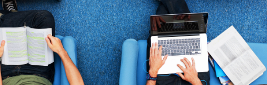 Two individuals sit in blue chairs with laptops, discussing retirement and reenrollment strategies for future planning.