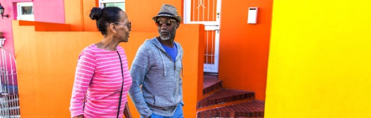 A man and woman stand before a vibrant building, symbolizing the importance of planning for hidden healthcare costs in retirement.