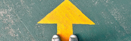 feet standing on arrow painted on sidewalk