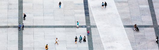 Aerial view of people walking in a bustling square, representing the potential of private markets to foster better retirement outcomes for individuals.