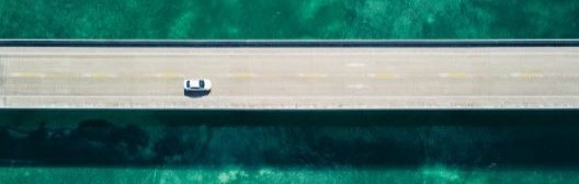 Aerial view of a small white vehicle on a road
