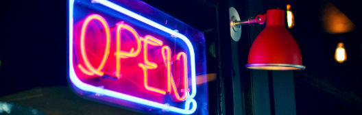 Neon "Open" sign in a window, symbolizing access to private markets in defined contribution plans.