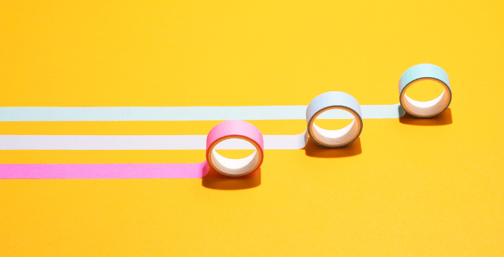Image of three rolls of tape rolling across a flat surface