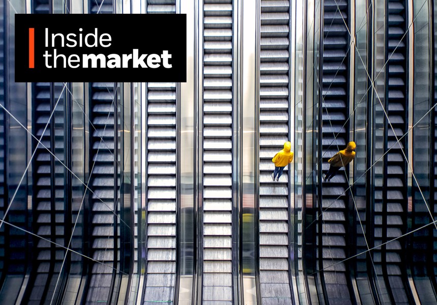 Person in a yellow raincoat going up an escalator