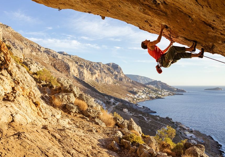 Person rock climbing on a cliff overlooking the sea