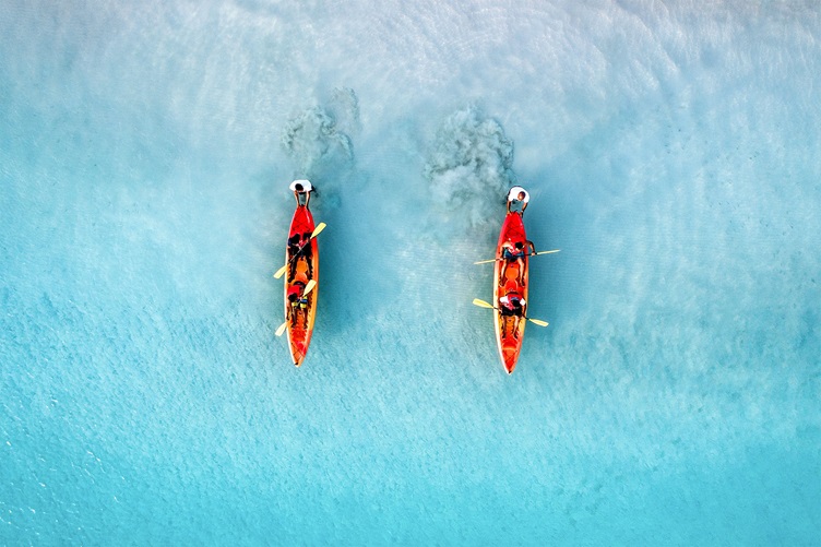 Two kayaks moving parallelly on clear water