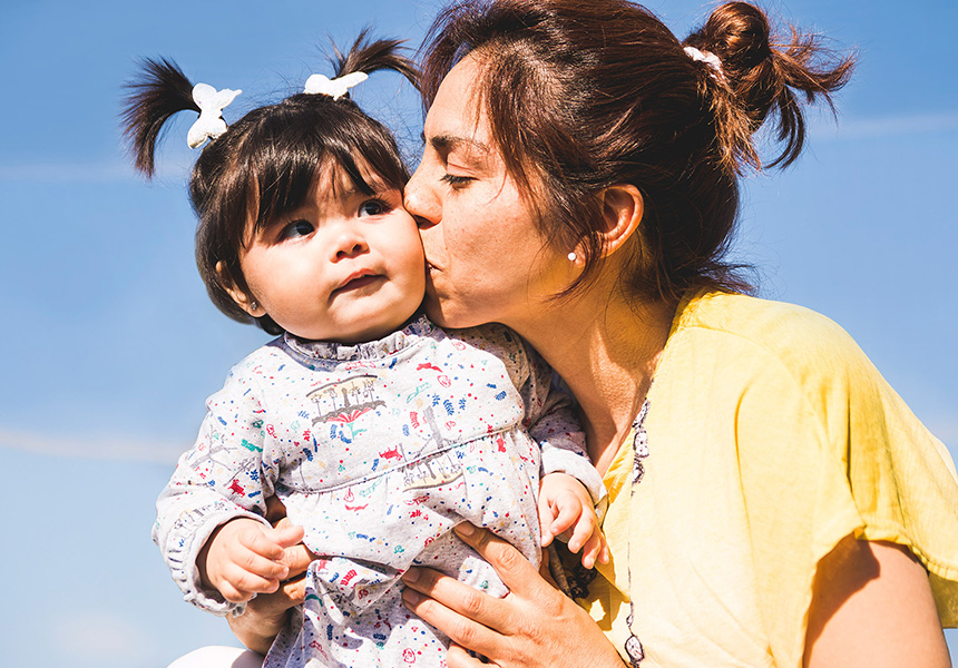 mom kisses her toddler daughter