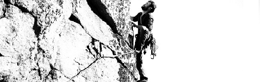 Climber scaling a steep rock face, symbolizing the pursuit of financial goals and overcoming market challenges.