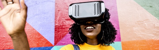 Person wearing a VR headset, raising a hand in front of a colorful mural.