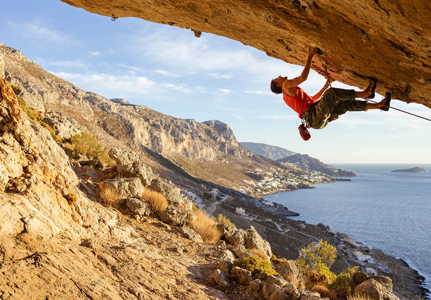 A photo shows a man climbing up a rock face.