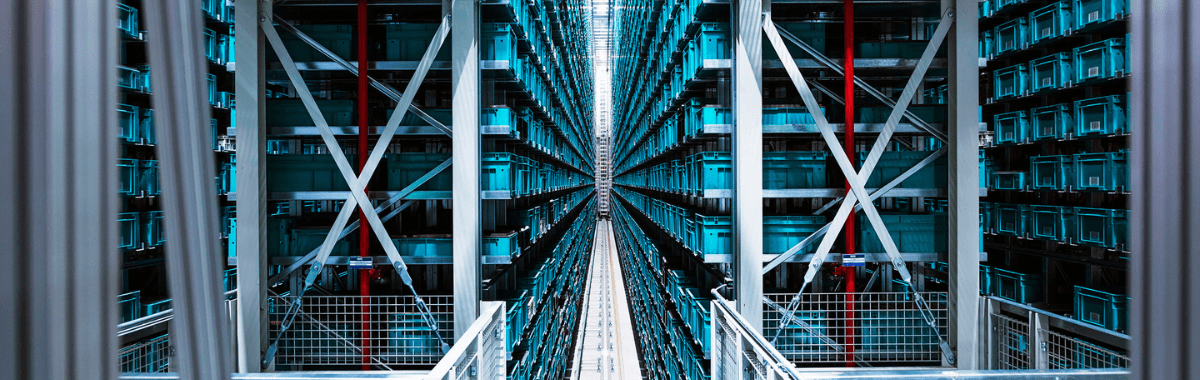 Warehouse aisle with tall automated storage racks and rows of blue bins.