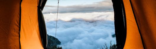 Image of open tent with view of clouds over mountain.