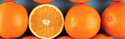 Decorative image of four oranges, one is cut in half.