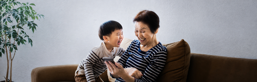 Grandmother and grandson smiling while looking at smartphone together