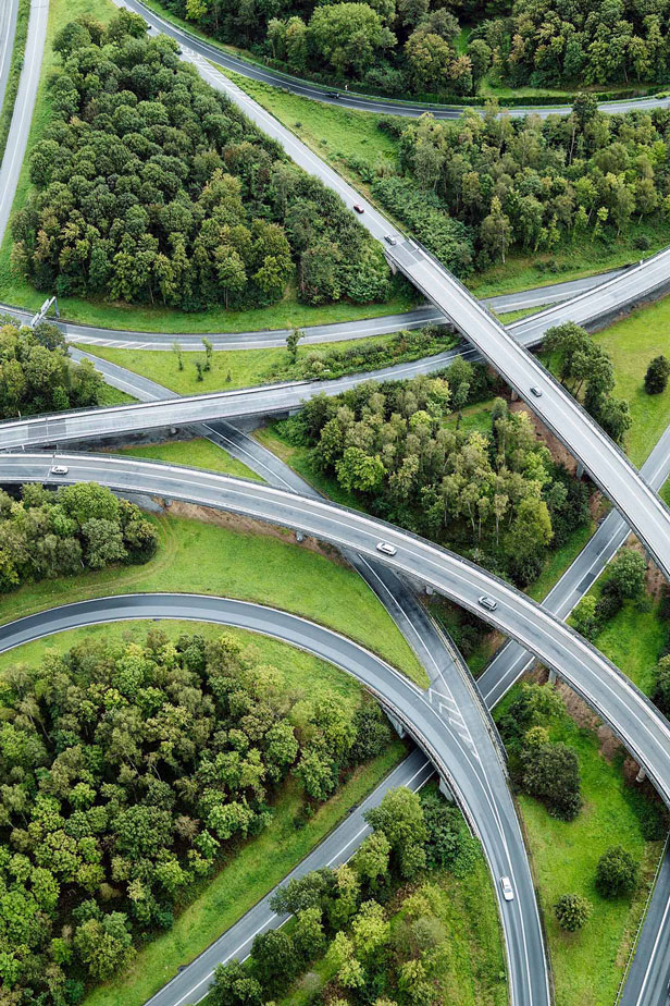 A complex highway interchange with multiple overpasses and underpasses surrounded by lush green vegetation.