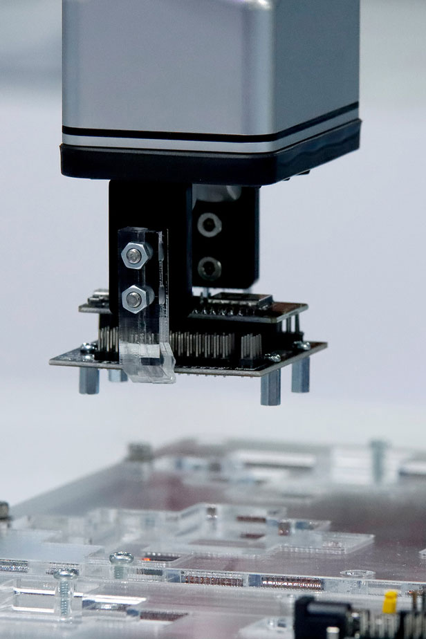 Robotic arm placing an electronic component onto a circuit board during assembly.