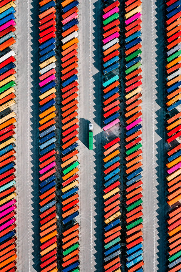Aerial view of rows of colorful shipping containers arranged in a large port or storage yard.