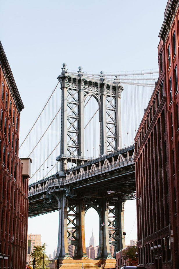 Manhattan Bridge framed between two red brick buildings.