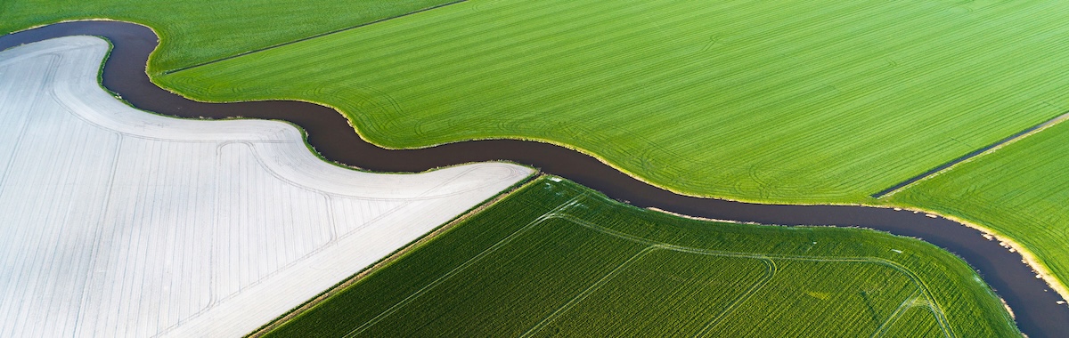 Aerial view of a winding river through green farmland