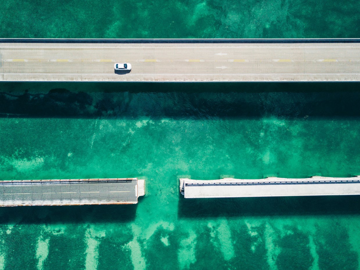 An image of two bridges, one is continuous with a car driving on it, the other is split
