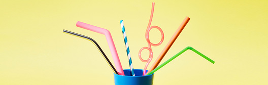 Multiple straws sitting in a blue cup.
