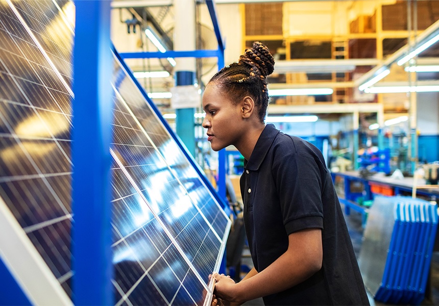 Woman inspecting solar panels in a manufacturing facility.