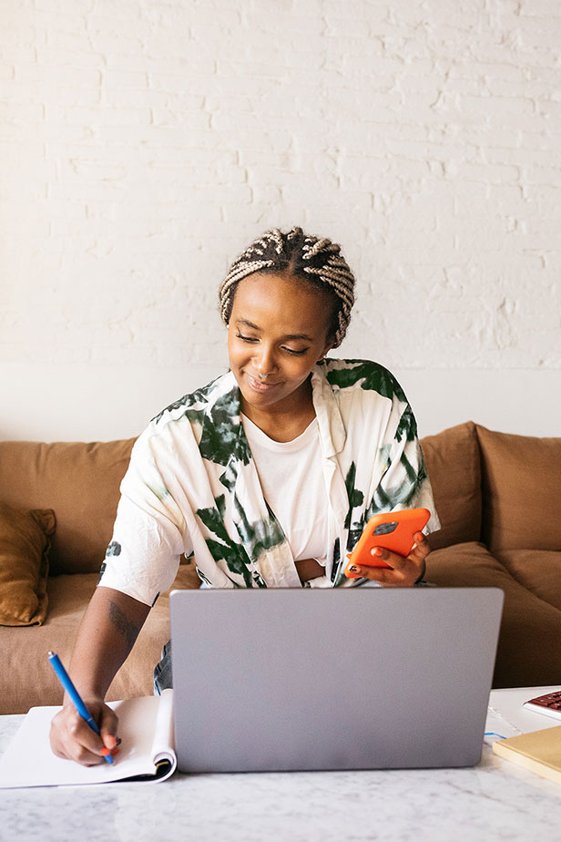 Woman sitting on sofa and using laptop at a marble table.