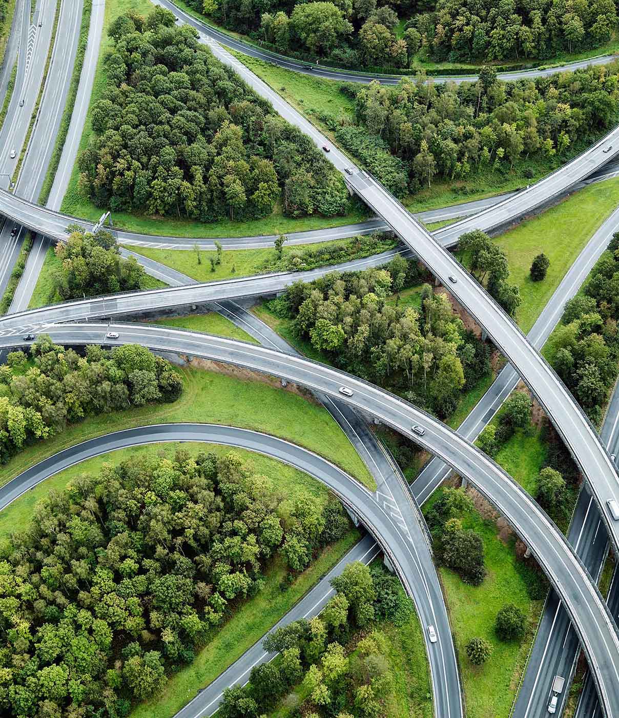 A complex highway interchange with multiple overpasses and underpasses surrounded by lush green vegetation.