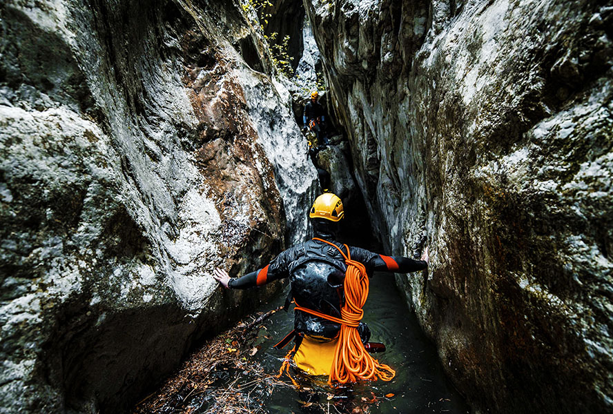 A canyoneering adventurist making his way through the wet gorge bottom