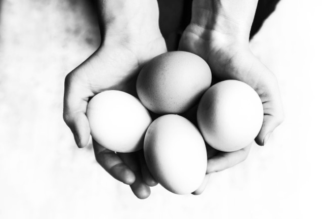 De handen van een persoon die vier eieren voorzichtig in de hand houdt