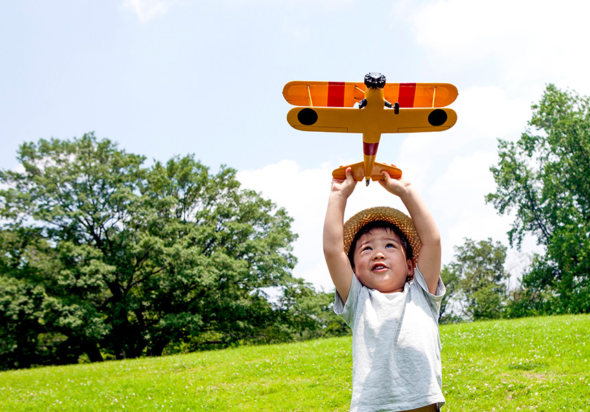 A young boy plays with a toy aeroplane.
