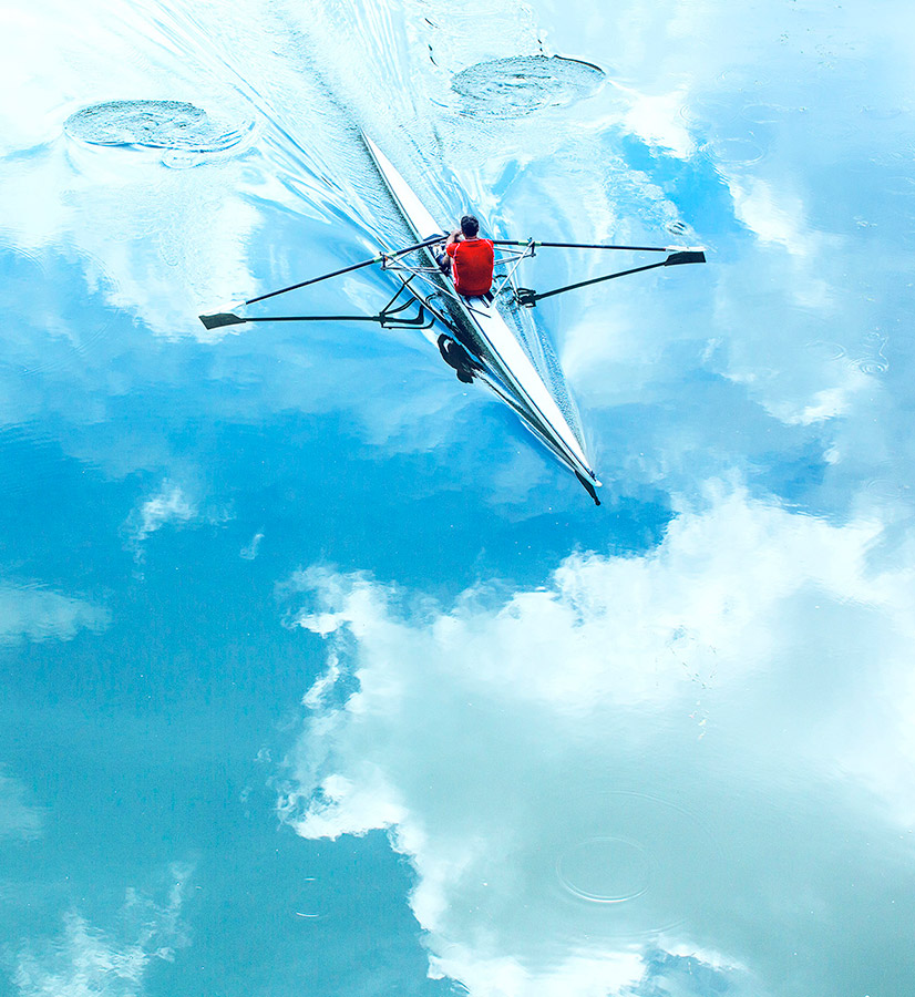 Image of man canoeing along a clear lake