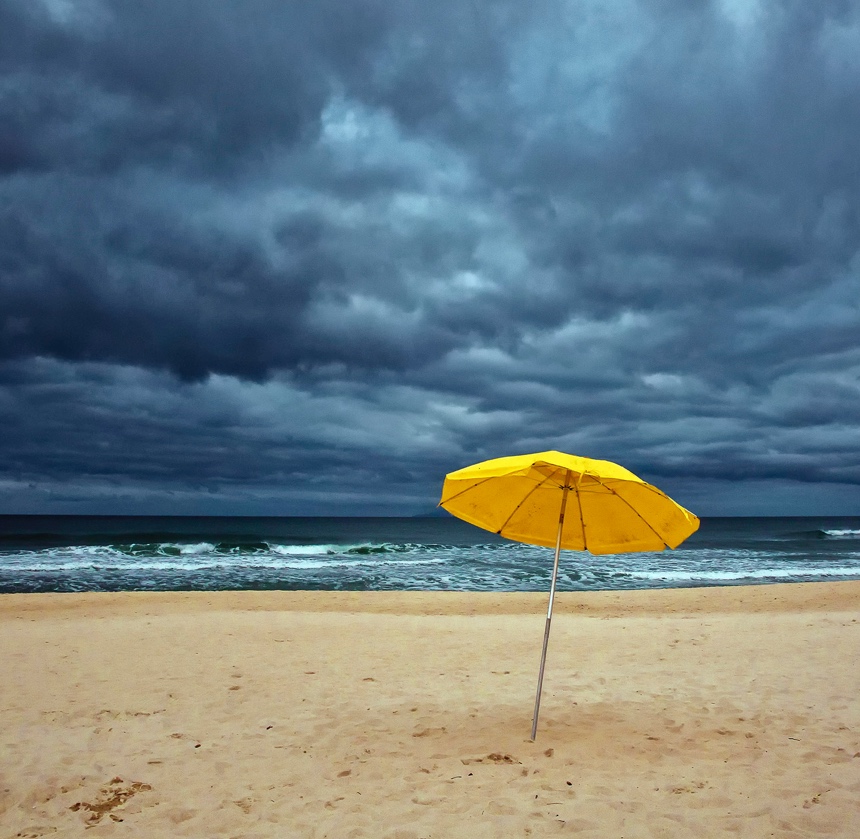 An single umbrella on the beach with an ominous sky