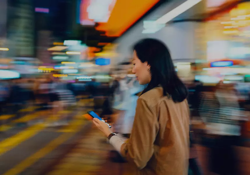 Lady looking at her cellphone on her hand with a fast paced background