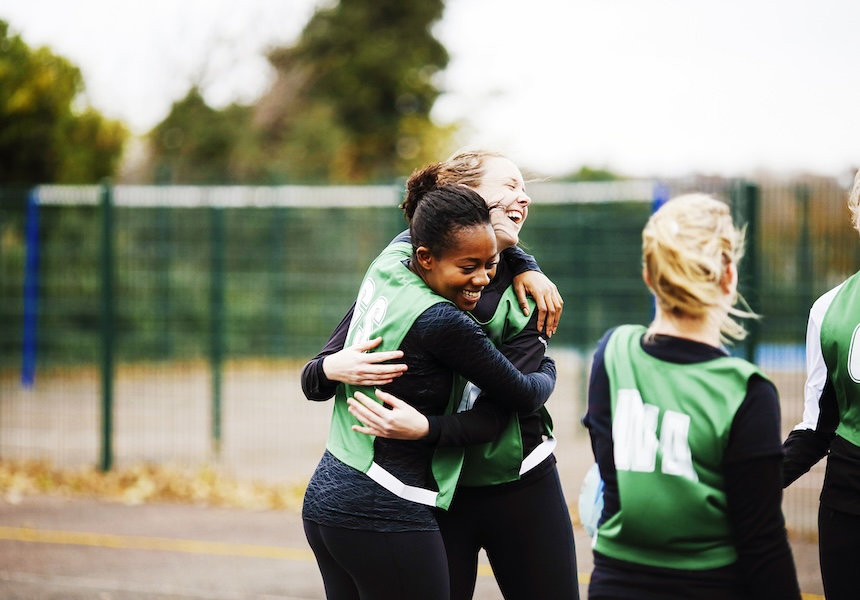 female team happily hugging in the field