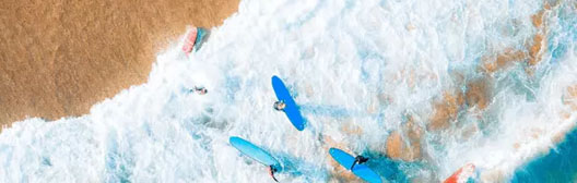 Eine Ansammlung von Surfbrettern an einem Strand aus der Vogelperspektive.