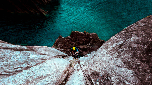 Image of a man rock climbing over water.