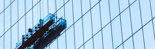 A person in a basket on a glass building