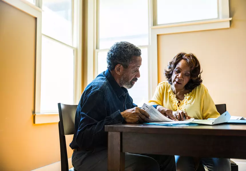 Two people are reviewing documents on table