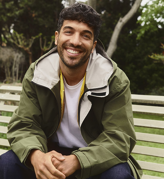 Ein junger Mann sitzt auf einer Bank im Park.