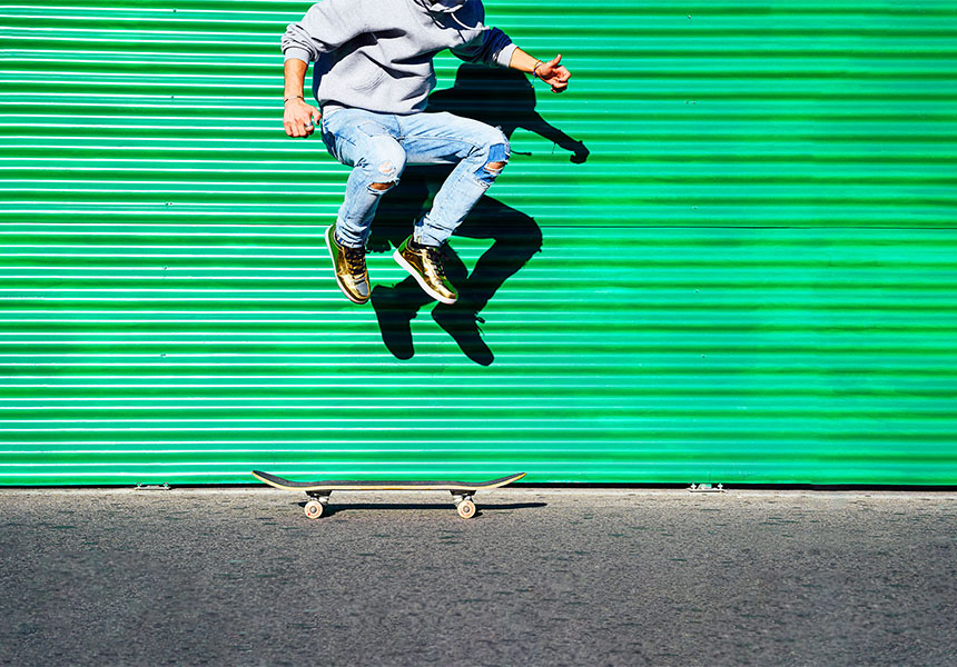 Ein Skateboarder springt in die Höhe vor einer grünen Wand