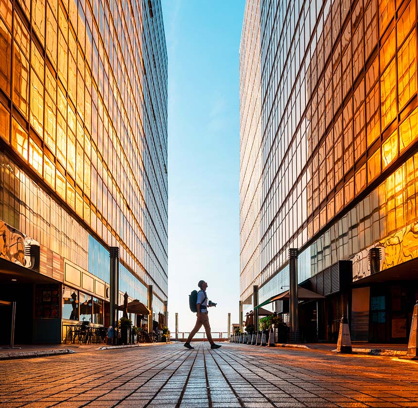un fotografo cammina tra due palazzi guardando in alto