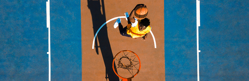 Mann wirft Ball in Basketballkorb