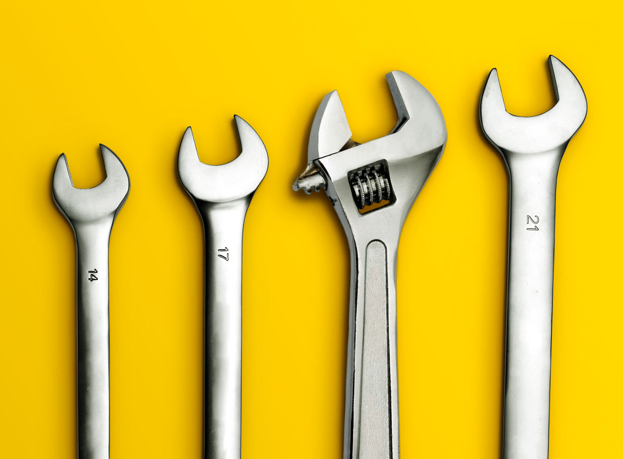 Abbildung von vier Schraubenschlüsseln auf gelbem Hintergrund.