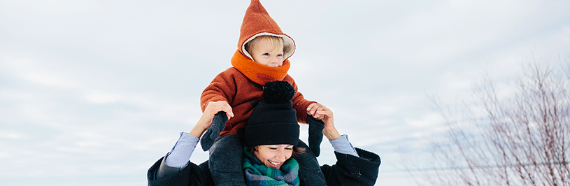 Frau mit Kind auf Schultern in winterlicher Kleidung