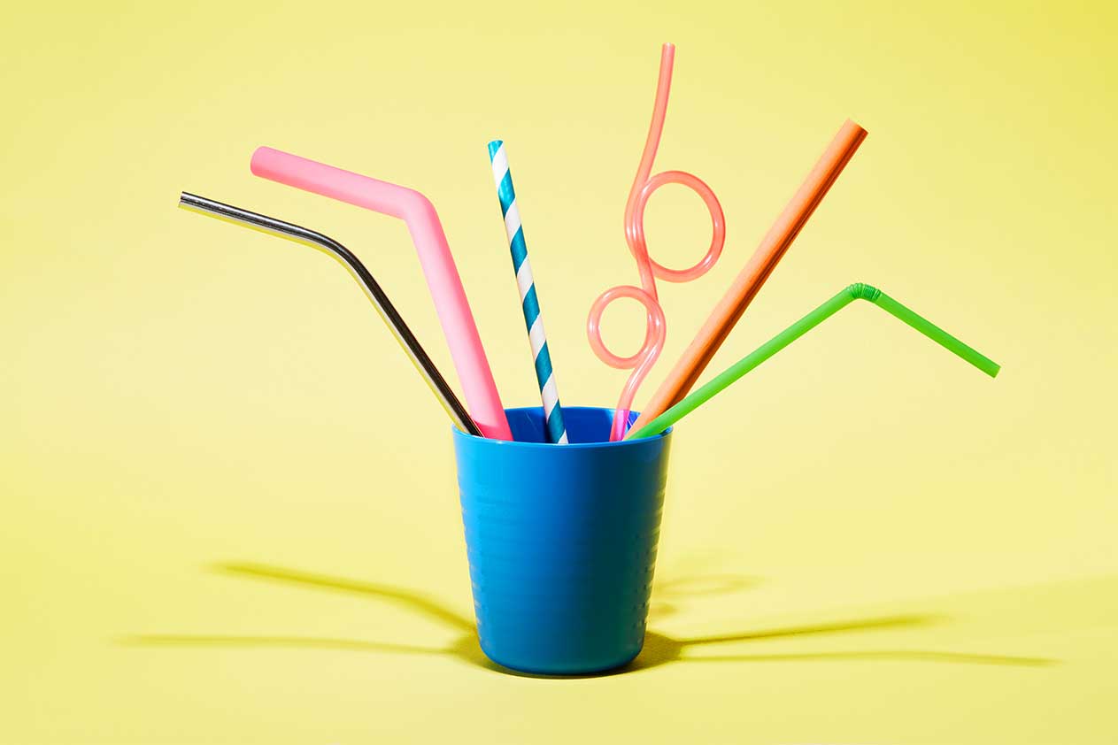 Photographie en gros plan de plusieurs pailles disposées en diagonale sur un fond neutre et doux, créant une composition épurée et minimaliste.