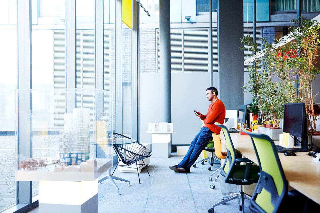 Person lehnt sich in einem modernen Büro an einen Tisch.