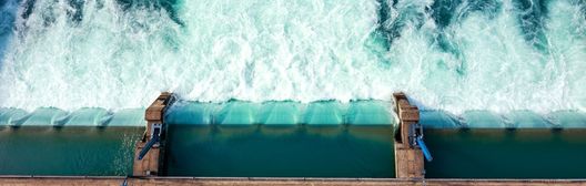 A strong wave crashes against the side of the dam.