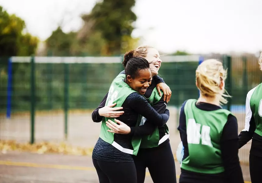 female team happily hugging in the field