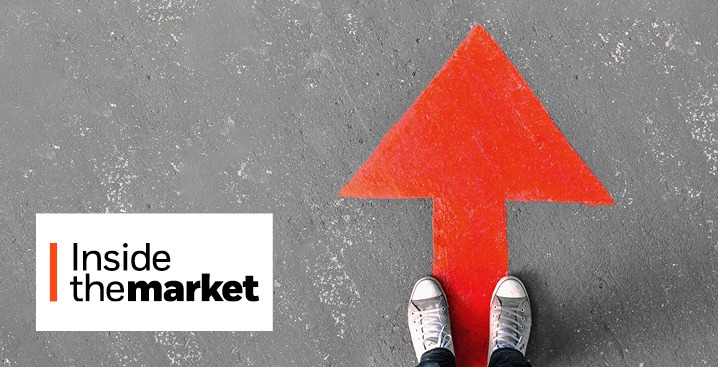 A person wearing sneakers stands on a large red arrow pointing upward on a grey pavement background, next to the text Inside the market.